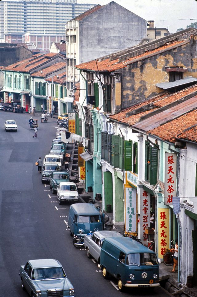 Hàng dài ô tô đỗ ngay ngắn bên lề đường. Những ngôi nhà gạch cũ kỹ nằm bên cạnh những tòa nhà chọc trời mới xây dựng ở Singapore.