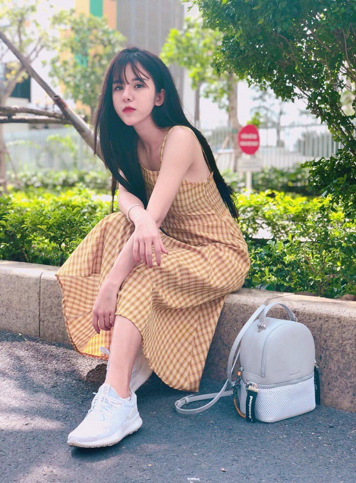 Cô mặc váy kẻ vàng hai dây hở lưng phối với giày sneaker trắng sành điệu.