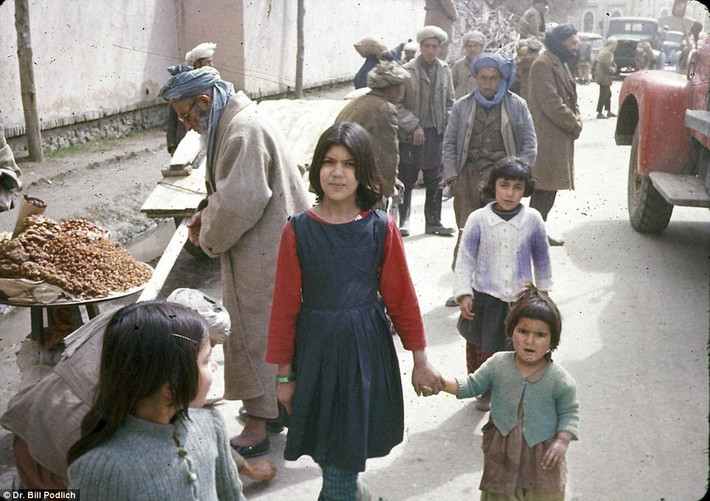 Hai chị em gái người Afghanistan dắt tay nhau đi qua một con phố buôn bán náo nhiệt ở Kabul.