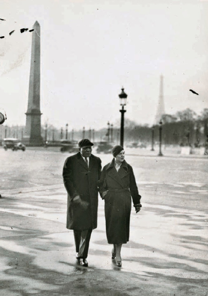 Võ sĩ quyền Anh người Mỹ Jack Johnson sánh bước đi bộ bên người vợ thứ hai Irene Pineau ở Paris, Pháp năm 1930.