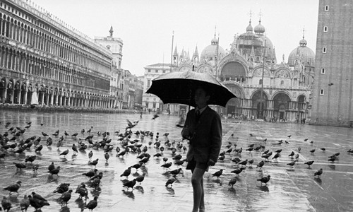 Nam học sinh đi bộ qua quảng trường Saint Mark, Venice, Italy năm 1958. Hình ảnh những chú chim bồ câu thường xuất hiện ở các quảng trường để tìm kiếm thức ăn đồng thời tạo nên điểm độc đáo, cuốn hút du khách.
