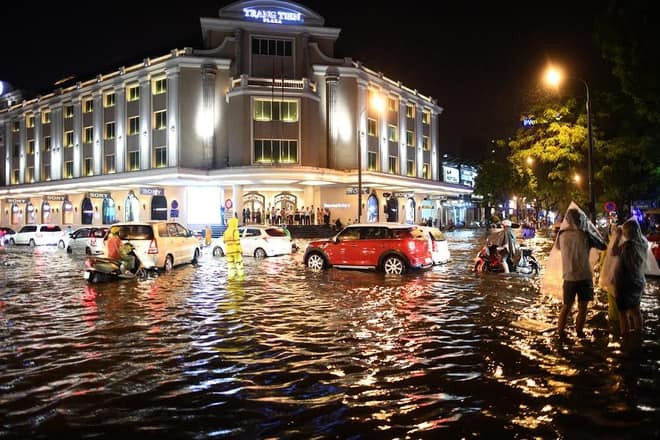 Sau cơn mưa nhưng nước vẫn chưa kịp rút, người và phương tiện di chuyển khó khăn tại khu vực Tràng Tiền.