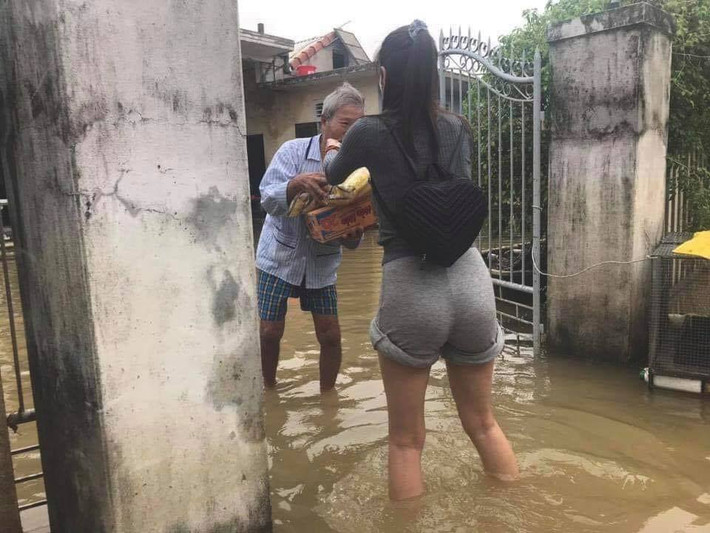 Nữ ca sĩ diện trang phục đơn giản, quần xắn cao qua gối để lội nước vào từng nhà dân tiếp tế lương thực và tiền cứu trợ.