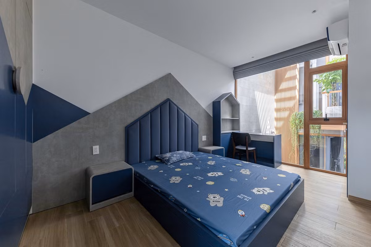 Phòng ngủ dành cho bé trai với tone màu xanh, hướng tầm nhìn ra khoảng thông tầng. Ảnh: Minq Bui