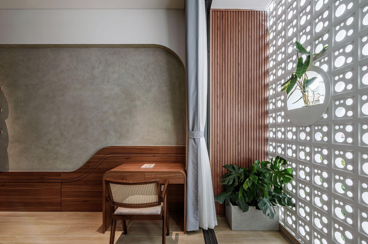 Góc làm việc đặt sát ban công, tận dụng ánh sáng tự nhiên lọc qua lớp gạch bông gió. Ảnh: LonTon Studio