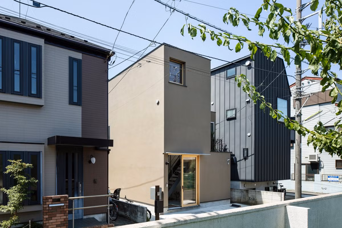 Mặt tiền hình chữ L được hoàn thiện bằng tông màu đất, mang đến sự hiện diện ba chiều nhẹ nhàng của cây xanh giữa cảnh quan thành phố. Ảnh: Kenta Hasegawa