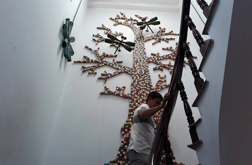 Một "cây gia đình" lớn khác cao hơn 4 m, được ghép ngay cầu thang tầng 3 bởi hàng ngàn nắp chai đủ màu sắc. Ảnh: Znews