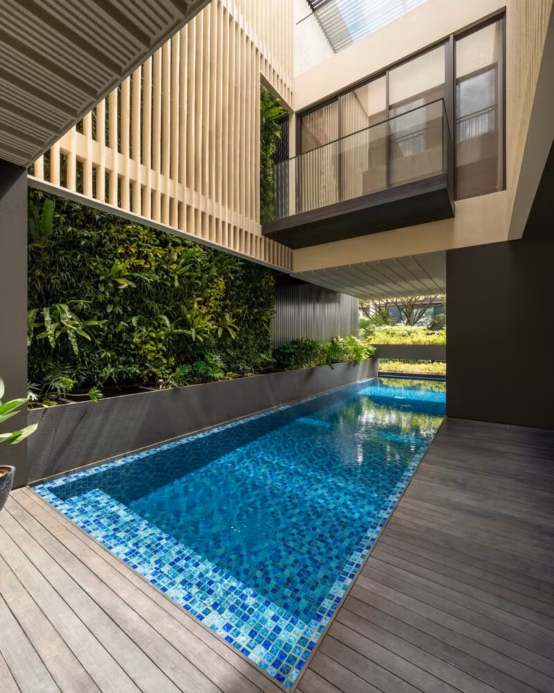 Do diện tích hạn chế, cây xanh được tích hợp dưới dạng bồn cây nhô ra ở mép trước của hồ bơi, không chỉ đóng vai trò như một lớp chắn thị giác và cách nhiệt với khu vực lân cận, mà còn là mái che cho khu vực để xe bên dưới. Ảnh: Arte Haus