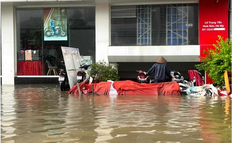 Người dân dựng tường chắn, bao cát trước cửa hầm nhà liền kề để nước không tràn vào. Một số gia đình lắp máy bơm để hút nước, nhưng mực nước trong hầm vẫn ngập từ 1-2m. Ảnh: Vietnamnet