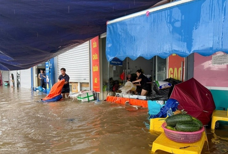 Nước ngập quá đầu gối, các hộ dân thuê kiot dưới chân chung cư Ecohome 3 dựng ván ngăn nước, đồng thời dùng xô chậu tát nước ra ngoài. Ảnh: Vnexpress