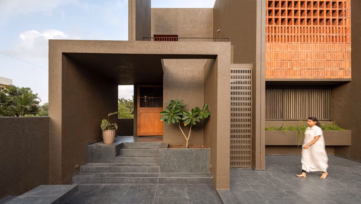 Bên ngoài căn nhà sử dụng tông màu đất chủ đạo và điểm nhấn là gạch thông gió màu cam. Ảnh: Archdaily