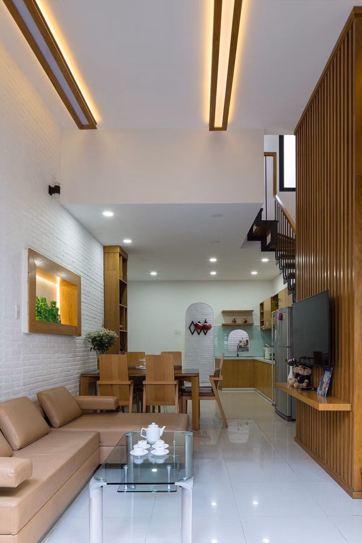 Tường, trần và sàn nhà sử dụng màu trắng sáng sủa kết hợp với đồ nội thất chất liệu gỗ được thiết kế đồng bộ từ vách ngăn, tay vịn cầu thang, cửa, kệ tủ bếp,...Ảnh: Quang Dam