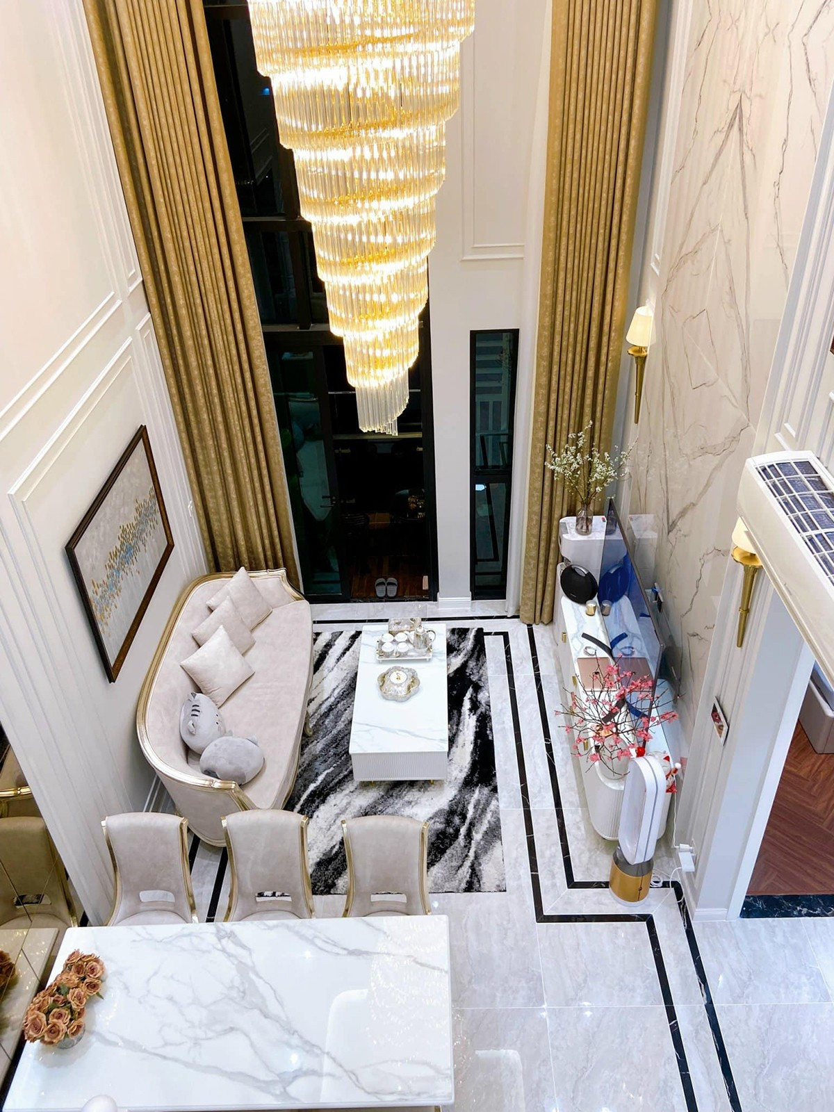 Căn hộ có gam màu trắng chủ đạo. Phòng khách với sofa, kệ ti vi, đèn trần thả, phong cách châu Âu. Ảnh: FBNV