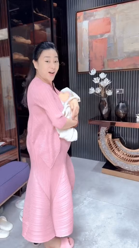 Khu vực sảnh chờ đơn giản với bức tranh nghệ thuật khổ to, một bàn tiếp đón nơi gia chủ trang trí hoa. Ảnh chụp màn hình