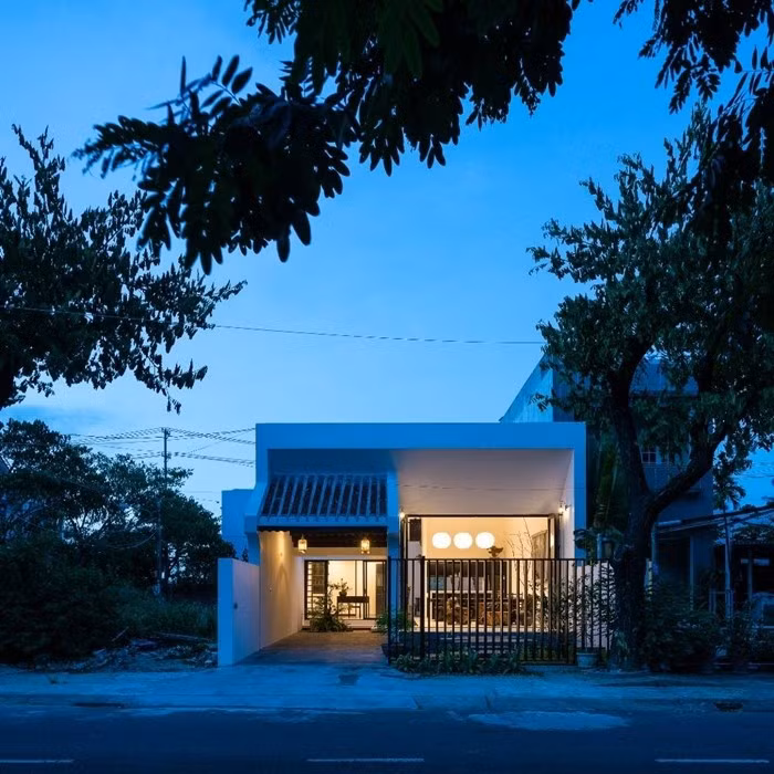 Ở mặt tiền, hai khối nhà có sự đối lập phong cách: hiên nhà phụ (khu vực gara) với kết cấu ngói âm dương truyền thống và hiên nhà chính với kiến trúc hiện đại. Ảnh: 6717 studio