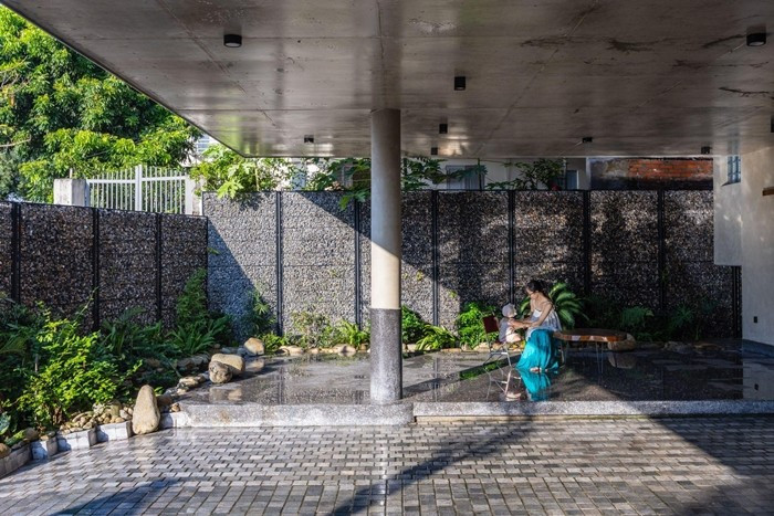 Khoảng sân lát gạch xám và mảng hiên gỗ trải dài tạo nên không gian đệm thư giãn trước khi bước vào nhà. Ảnh: Trieu Chien