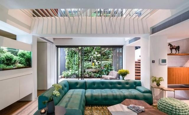 Sofa xanh trong phòng khách có cửa sổ được mở ở vị trí thấp, giúp gia chủ khi ngồi xuống có thể nhìn thấy sân sau. Ảnh: Toutiao