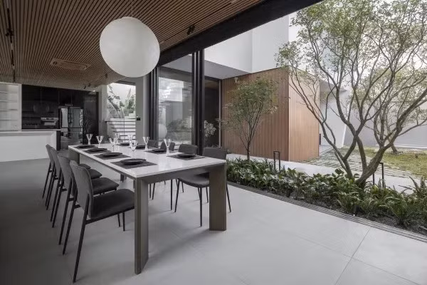 Bàn ăn đặt cạnh cửa kính lớn mở ra khu vườn xanh. Ảnh: Goku Agency