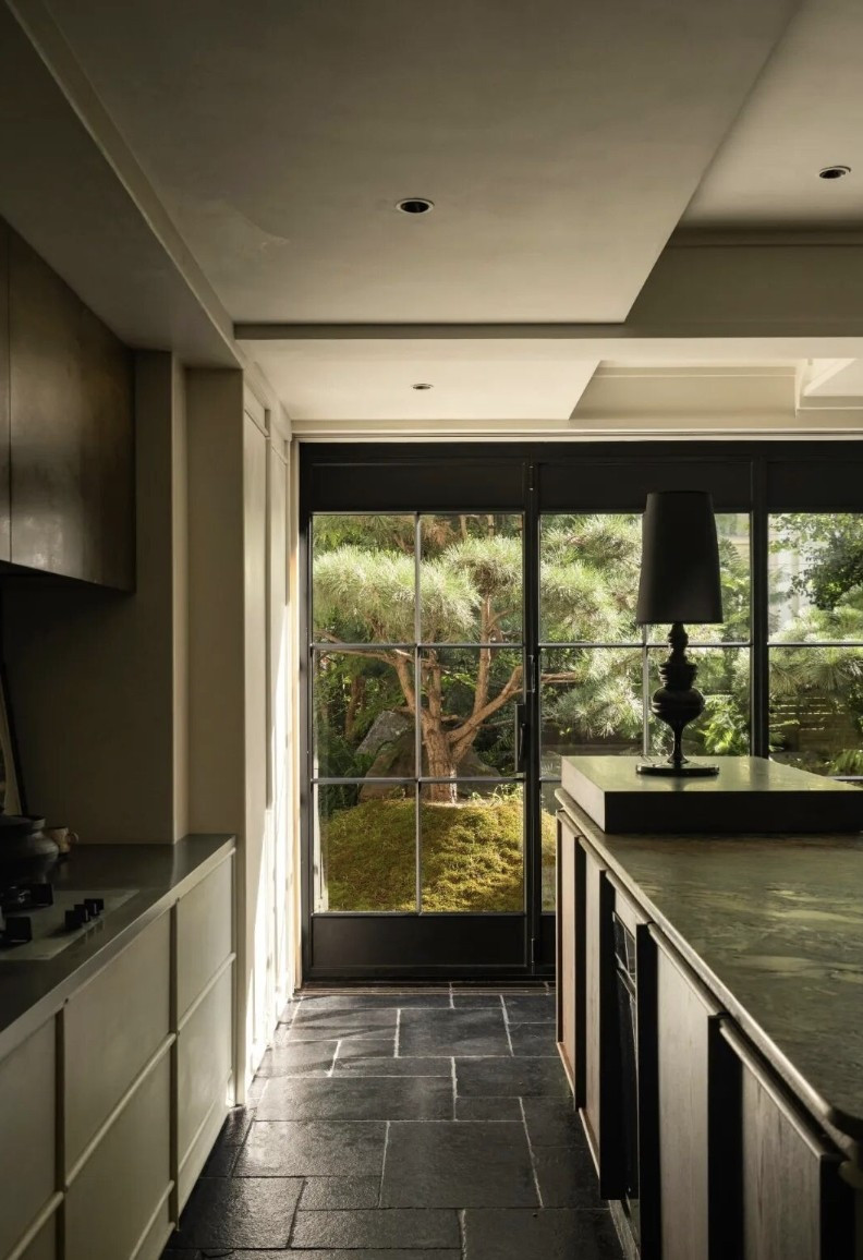 Để giải quyết vấn đề thiếu sáng, cặp đôi mạnh tay thay đổi cấu trúc không gian. Từ một phòng khách có cửa sổ rộng 4m và bếp kín, cặp đôi mở rộng toàn bộ khu vực bếp - phòng khách, tạo ô cửa sổ ngang dài hơn 7m, đưa trọn khung cảnh khu vườn vào trong nhà. Ảnh: Toutiao