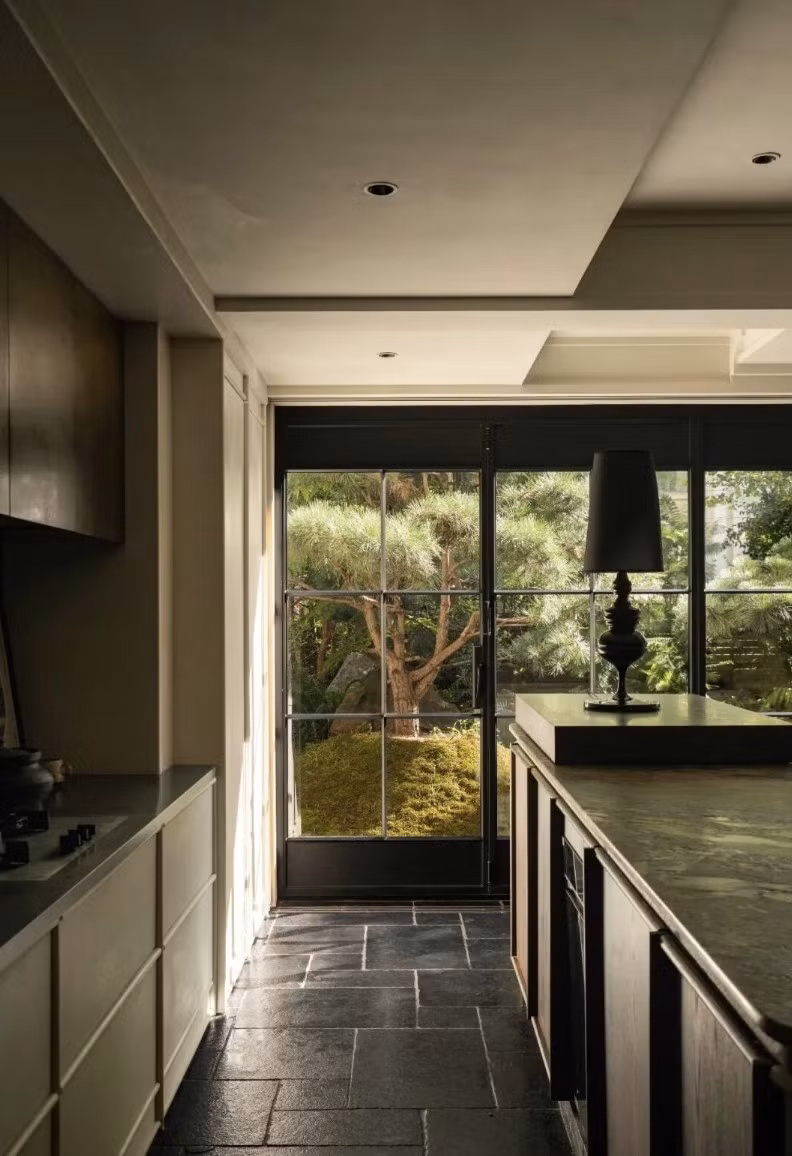 Để giải quyết vấn đề thiếu sáng, cặp đôi mạnh tay thay đổi cấu trúc không gian. Từ một phòng khách có cửa sổ rộng 4m và bếp kín, cặp đôi mở rộng toàn bộ khu vực bếp - phòng khách, tạo ô cửa sổ ngang dài hơn 7m, đưa trọn khung cảnh khu vườn vào trong nhà. Ảnh: Toutiao