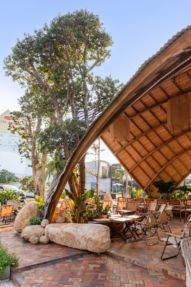 Ánh sáng tự nhiên chiếu vào không gian từ sáng đến chiều muộn làm nổi bật sự tương tác giữa các khối hình bất đối xứng của quán cà phê và đường mái kéo dài. Ảnh: Minq Bui