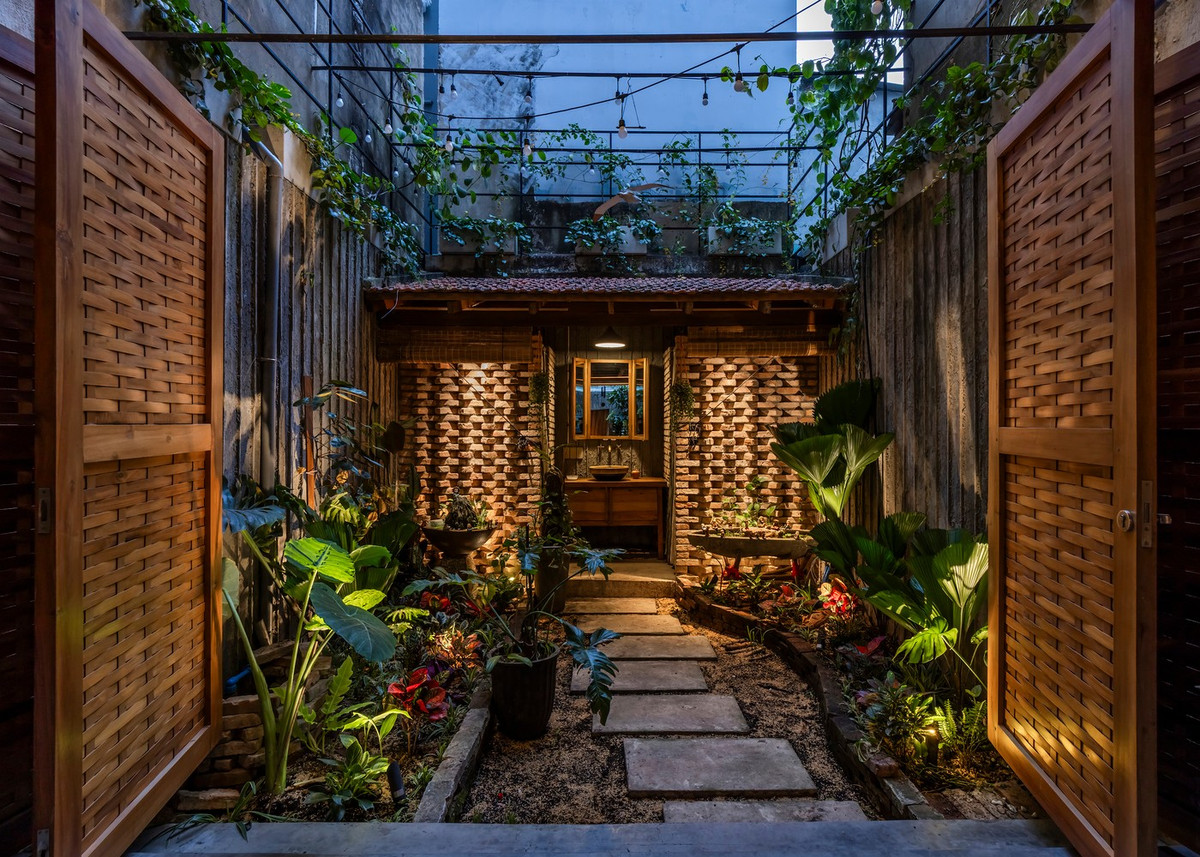 Gần đó, phòng tắm và nhà vệ sinh được bố trí ngoài trời, có mái che nhưng vẫn thoáng đãng, kết nối với nhà bằng một lối đi đơn giản xuyên qua khu vườn. Ảnh: Hirouyki Oki