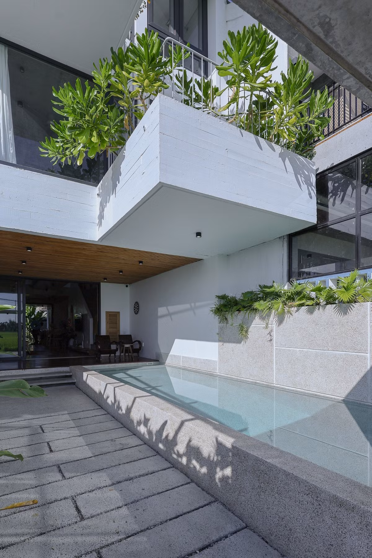 Tầng trệt bố trí các không gian mở liên tục, có tính kết nối như: hiên nhà, hồ bơi, khu vườn nhỏ trước sau, khách và bếp, tạo ra sự lưu thông không khí từ cánh đồng vào nhà và thoát ra sau vườn. Ảnh: Sukha Studio.