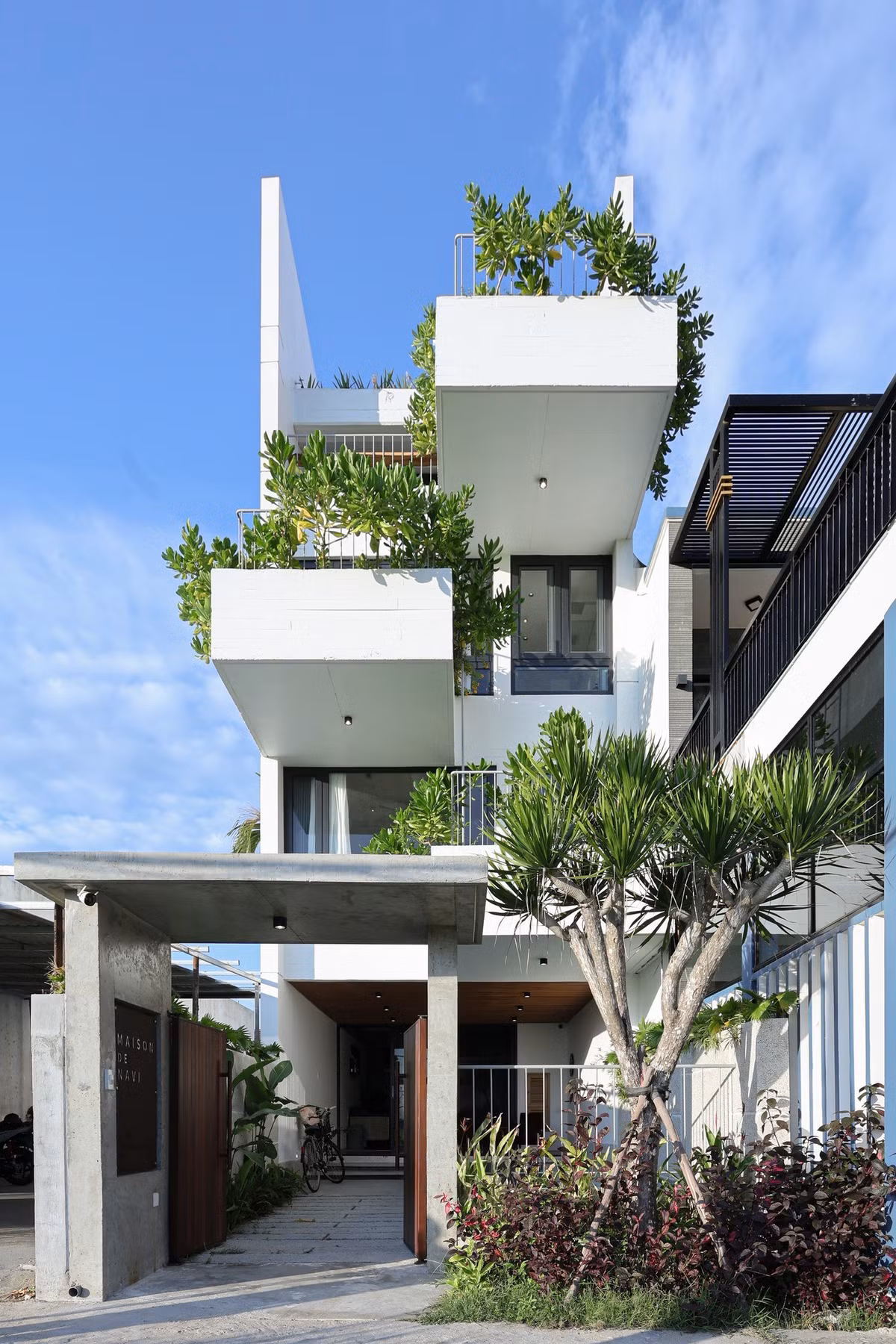 Ban công kết hợp “chậu cây” vừa đóng vai trò là vùng đệm giảm bức xạ nhiệt, vừa tạo lớp bảo vệ khỏi gió mạnh, và giúp công trình có sự gắn kết với cảnh quan đồng ruộng bao quanh. Ảnh: Sukha Studio.