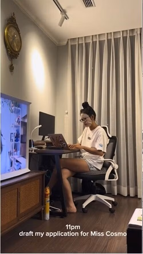 Phòng làm việc đơn giản gồm bàn gỗ tối màu, rèm cửa lớn. Ảnh chụp màn hình