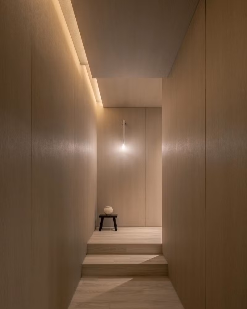 Hành lang lệch tầng với ánh sáng hắt trần và tường gỗ đồng bộ tạo cảm giác mềm mại. Ảnh: Joel Moritz