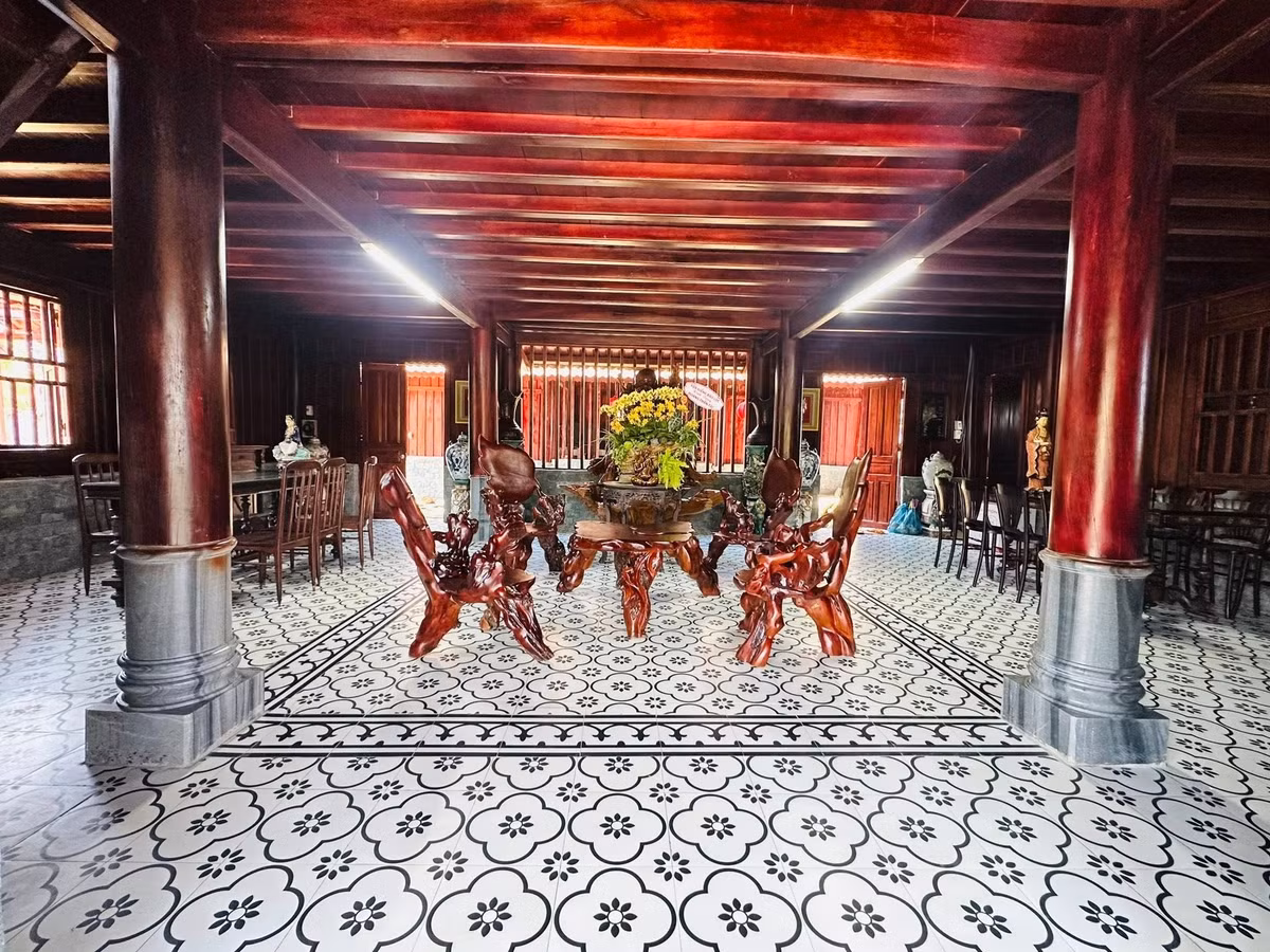 Bộ bàn ghế gỗ chạm khắc tinh xảo đặt trên nền gạch hoa cổ điển, toát lên vẻ sang trọng và hoài niệm. Ảnh: FB Hoàng Minh Bùi