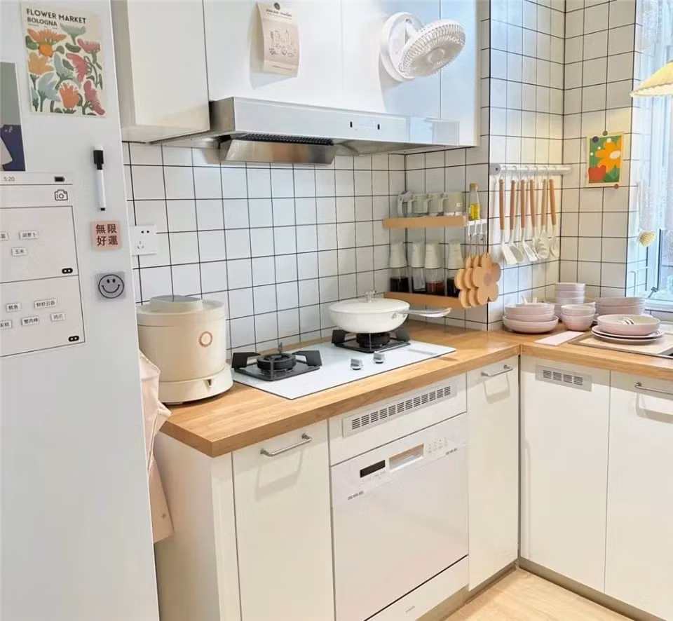 Bếp đặt cạnh tủ lạnh, hai bên là tủ lưu trữ. Một bên bếp hình chữ U có một mặt bàn tủ nhỏ. Máy rửa bát được lắp âm dưới bếp, mặt bàn trống thoáng. Ảnh: QQ