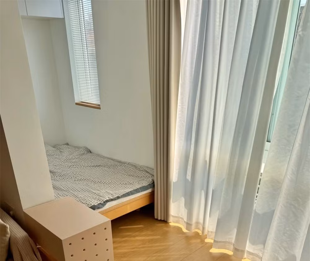 Ấn tượng nhất là phòng ngủ phụ có ban công dài 1,2m. Một bên cô đặt máy giặt – kết hợp làm tủ lưu trữ. Bên còn lại, cô đặt vừa khít một chiếc giường đơn dài hơn 2m, phía trên là tủ treo nhỏ. Ảnh: Sohu