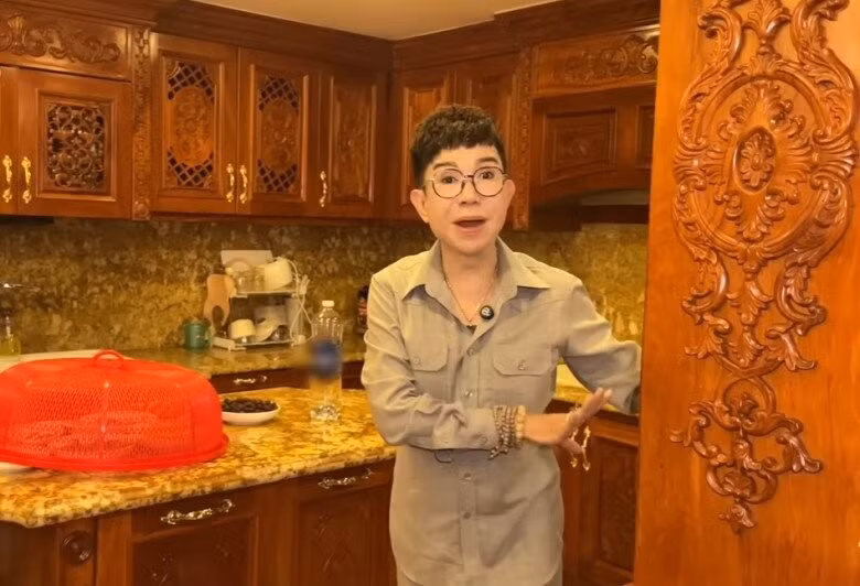 Phòng ăn và bếp rộng rãi với nội thất gỗ và ánh đèn vàng, mang lại cảm giác ấm áp. Ảnh chụp màn hình