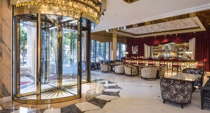 Không gian sảnh khách sạn Capella Hanoi Hotel như một nhà hát châu Âu thập niên 1920 với trần cao, đèn chùm pha lê, tường ốp gỗ sẫm và điểm xuyết bởi tượng nghệ sĩ opera. Ảnh: Yiwin