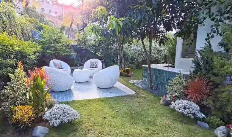 Không gian tiếp khách ngoài trời nổi bật với bộ ghế hình khối tròn, nền gạch xanh lam. Ảnh chụp màn hình