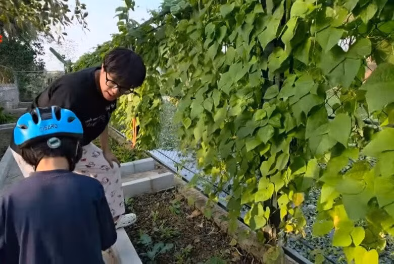 Minh Bủm và em út Bão bên giàn đỗ xanh mướt, trĩu quả. Ảnh chụp màn hình