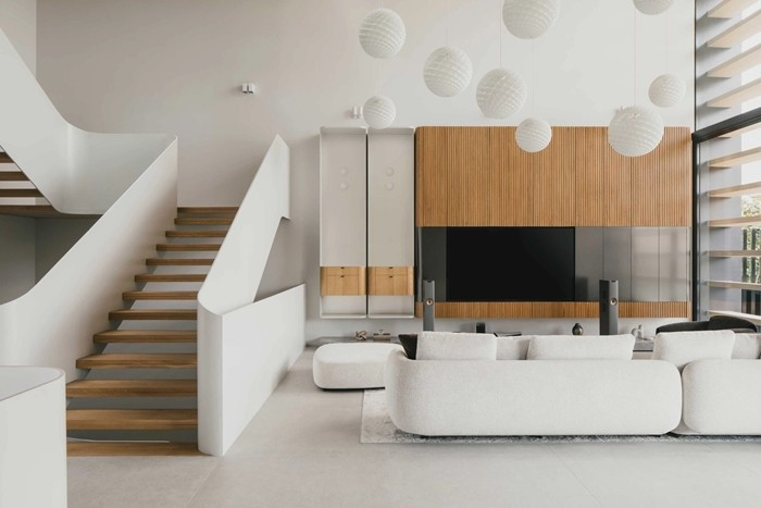 Phòng khách thông tầng đặt ở tầng 2, đóng vai trò trung tâm không gian. Trong phòng trang trí hệ đèn thả và cửa sổ mặt tiền cao tương ứng, cho phép ánh sáng tự nhiên đi sâu vào bên trong. Ảnh: Archello