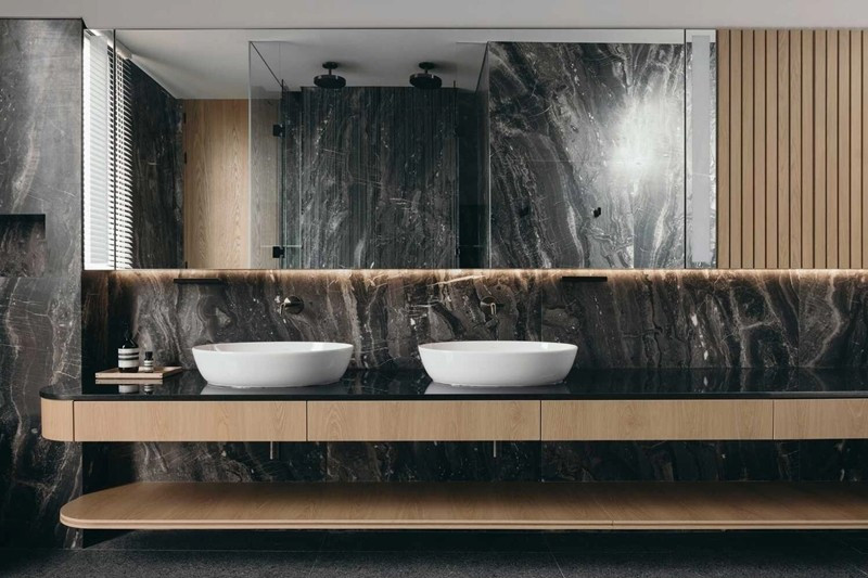 Khu vệ sinh sử dụng đá tự nhiên tông tối ốp toàn bộ tường và mặt bàn. Ảnh: Archello
