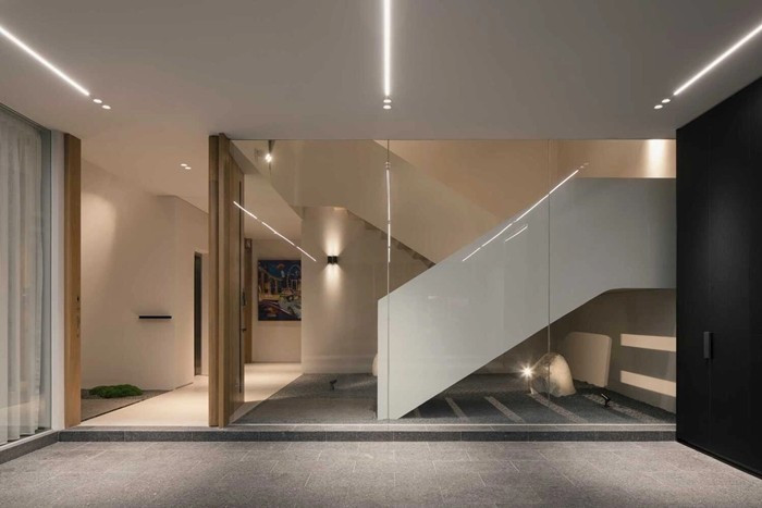 Cầu thang chính được thiết kế như một yếu tố kiến trúc nổi bật, kết nối các tầng đồng thời lấy ánh sáng từ giếng trời phía trên xuống. Ảnh: Archello