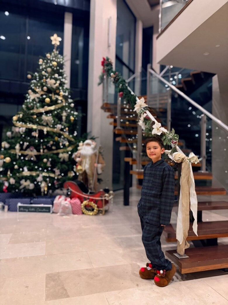 Tại khu vực sảnh, cầu thang kính trong nhà được trang trí công phu với cây thông xanh, nơ lớn và ruy băng. Ảnh: Thuy Tien Mfas