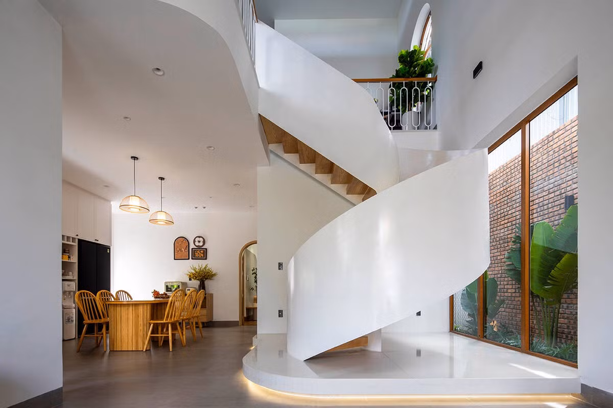 Điểm nhấn kiến trúc là cầu thang xoắn trắng tinh, vừa là trục giao thông đứng, vừa đóng vai trò như một tác phẩm điêu khắc nội thất. Ảnh: Khánh Nguyễn