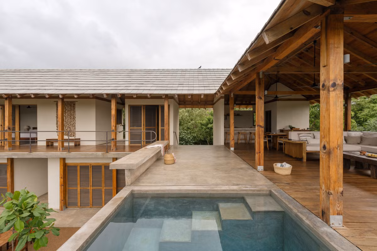 Hồ bơi và khu sinh hoạt chung trên tầng chính kết hợp mái gỗ truyền thống và sàn bê tông hiện đại. Ảnh: Archello