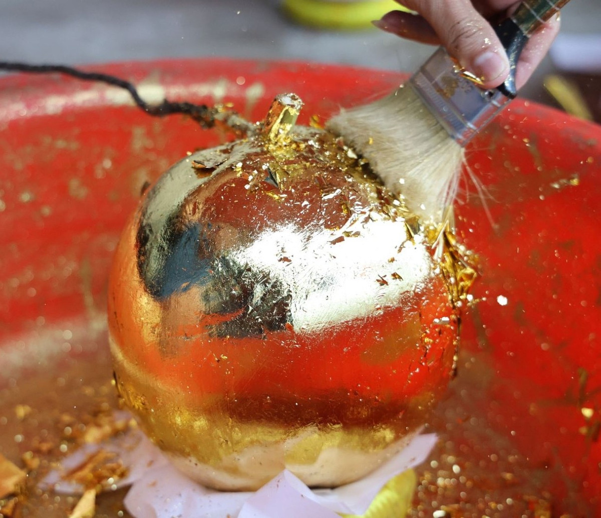 Sau khi rửa sạch, dừa được phết keo, phơi khô rồi dát vàng. Ảnh: Báo tin tức