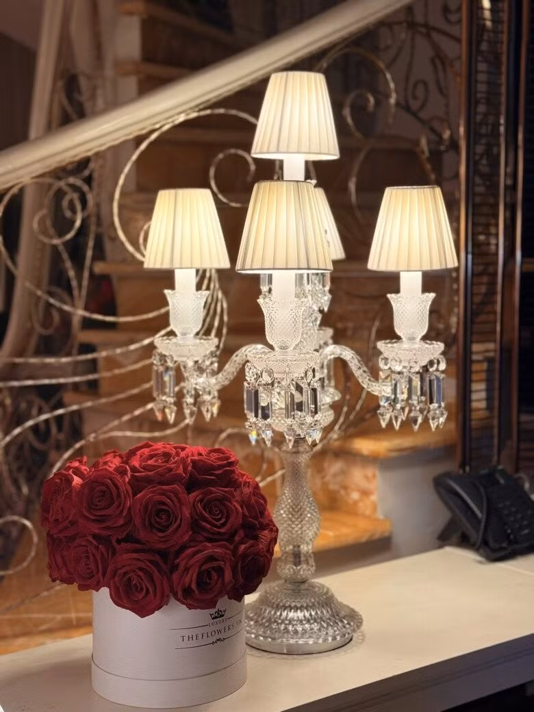 Đèn bàn pha lê cổ điển 5 bóng đặt cạnh hộp hoa hồng đỏ sang trọng, tạo góc decor như khách sạn cao cấp. Ảnh: FBNV