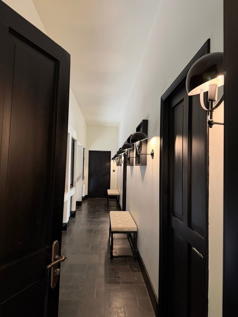 Hành lang dẫn vào các phòng gây ấn tượng bởi sự tương phản sắc nét giữa hệ cửa gỗ đen tuyền và tường trắng kem. Ảnh: FB Chi Bảo