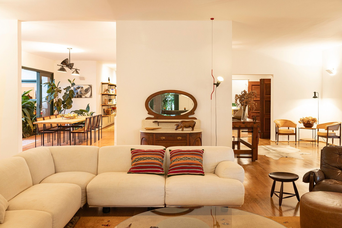 Bức tường sơn trắng đóng vai trò nền trung tính, làm nổi bật đồ gỗ, tranh nghệ thuật và các chi tiết có màu sắc trầm, ấm. Ảnh: Joana França