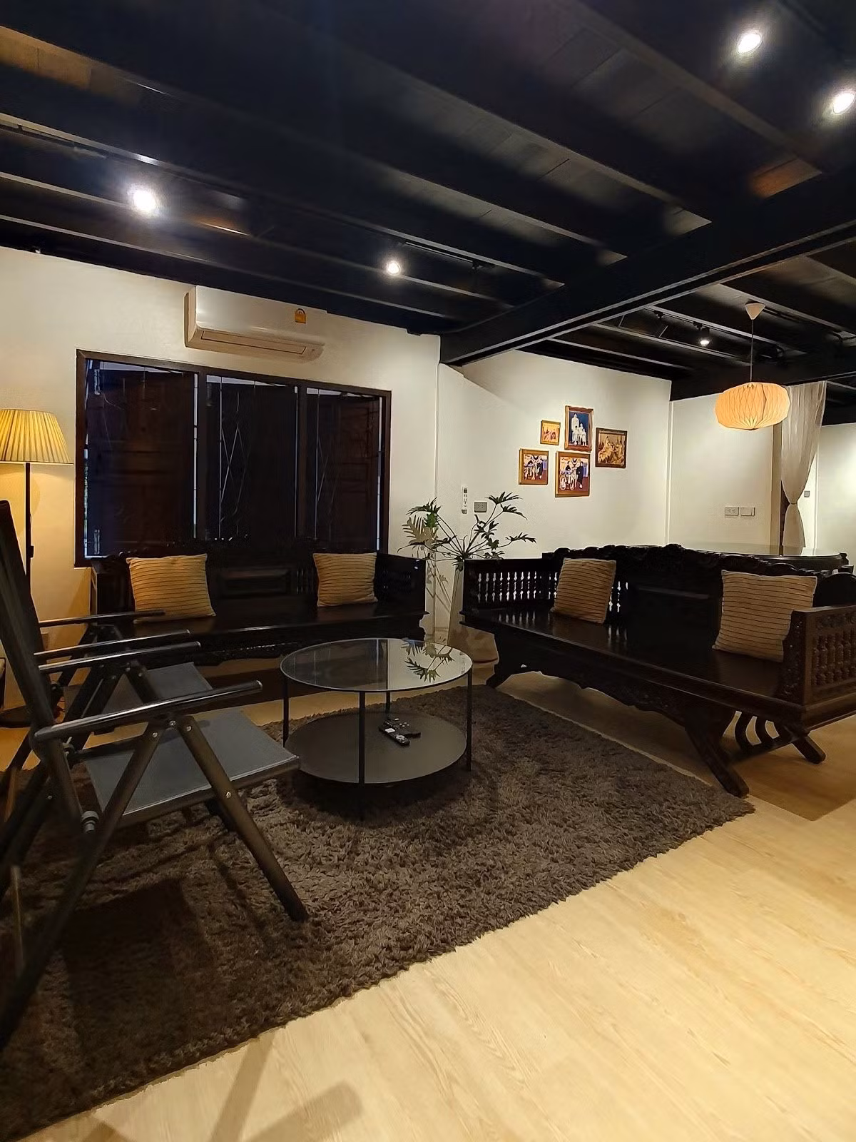 Sofa gỗ chạm khắc cùng ghế gấp hiện đại trong phòng khách. Ảnh: Homedeedee