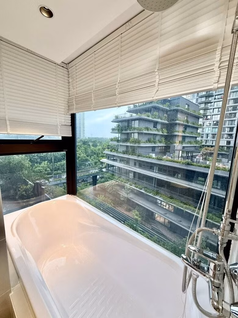 Bồn tắm đặt ngay bên khung kính lớn với tầm nhìn ra tòa nhà nhiều cây xanh. Ảnh: FBNV