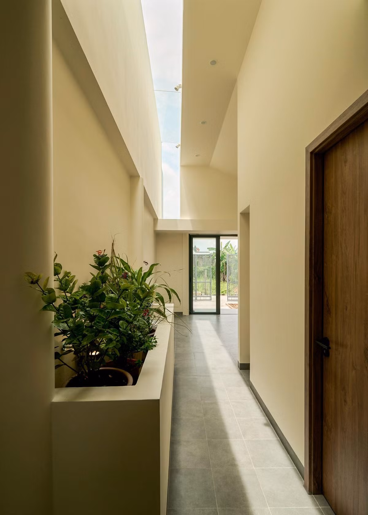 Khe sáng được bố trí khéo léo giáp vách tường cao của nhà bên cạnh, giúp cắt nắng sau giờ trưa và tận dụng ánh sáng tự nhiên vừa đủ. Ảnh: Nam Võ